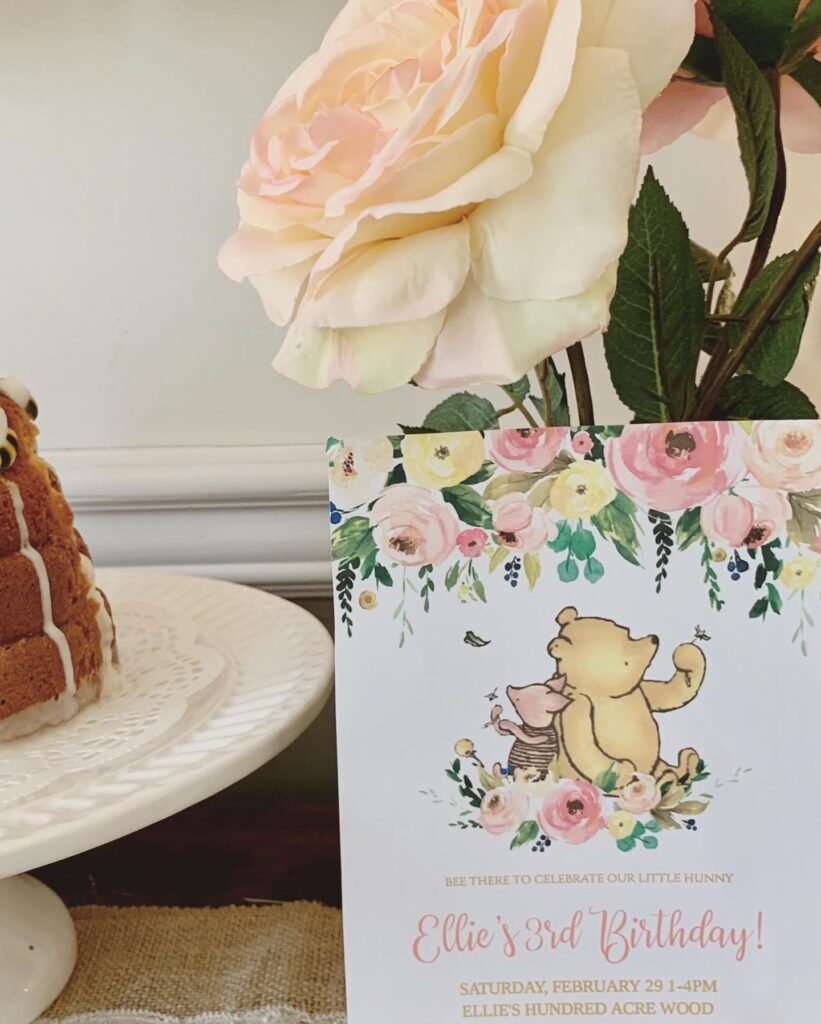 Winnie the Pooh birthday party invitation on desert table with florals