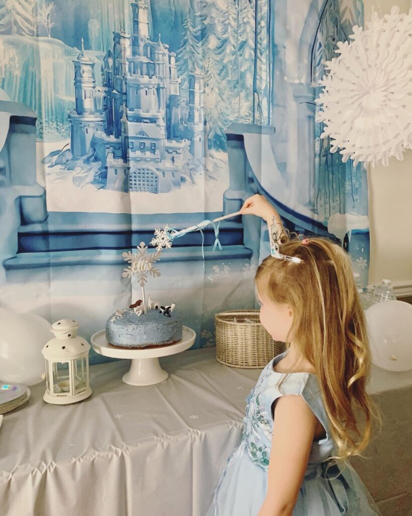 DIY winter princess party dessert table and cake with snowflakes and winter backdrop