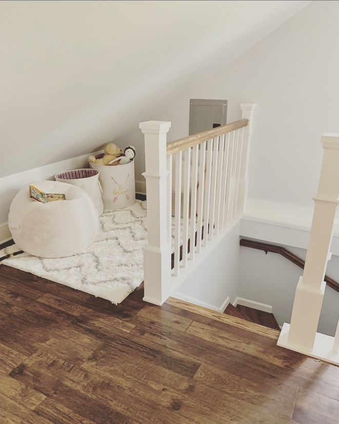 Cozy reading nook top of attic staircase with toy baskets and bean bag chair