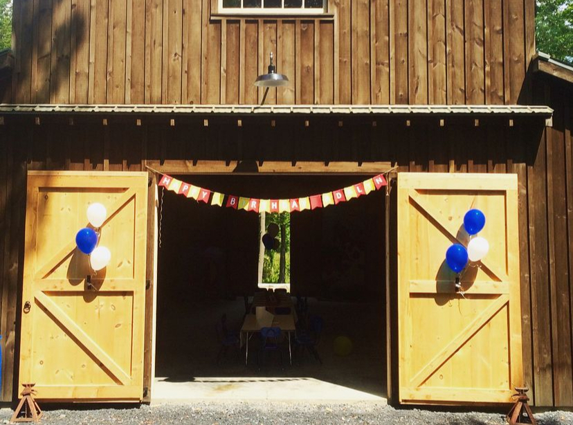 Pooh bear party Happy Birthday banner hanging on barn doors with balloons