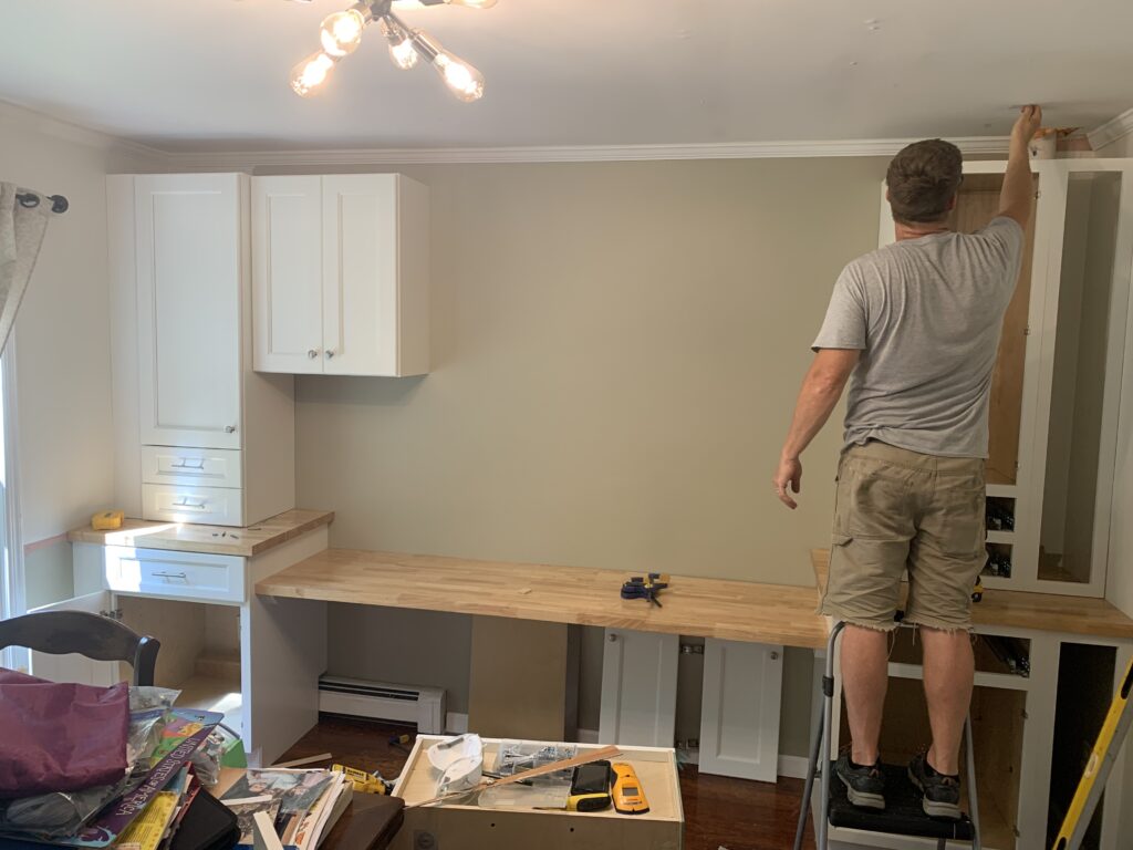 Builder installing custom cabinet in homeschool room renovation