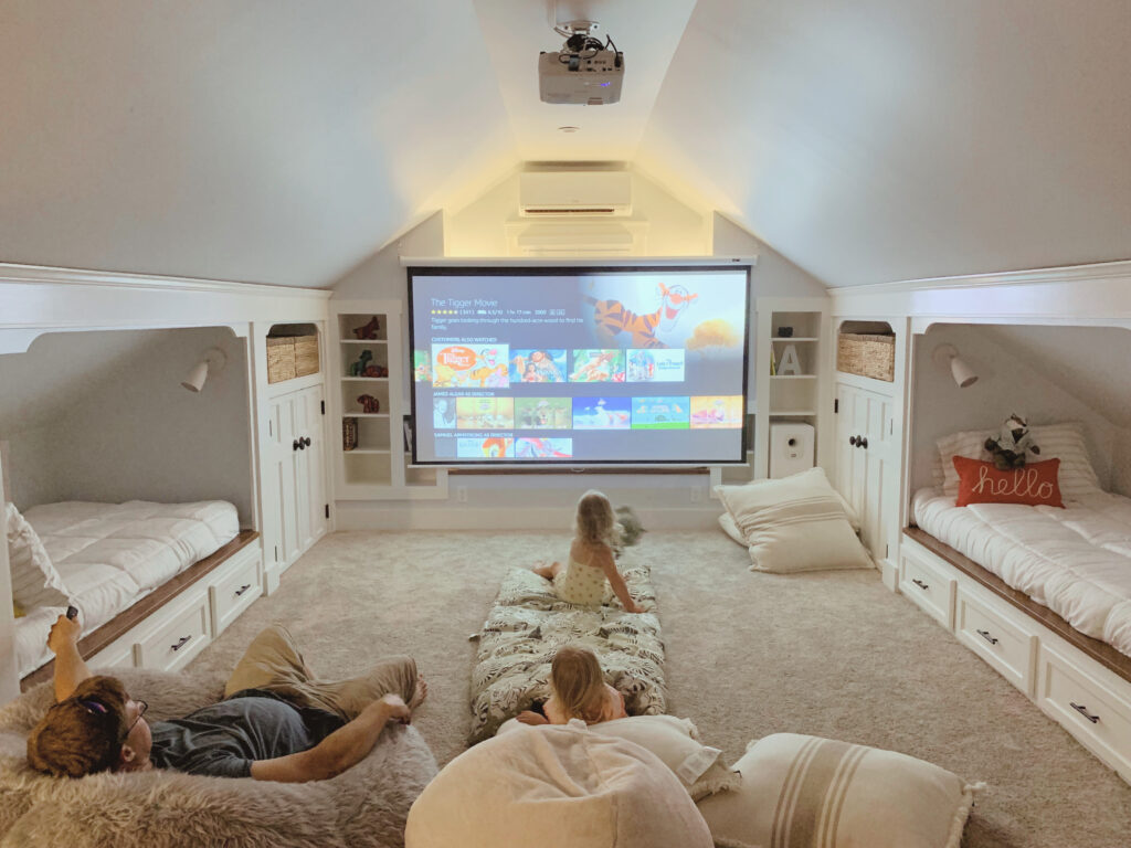 Home theatre in attic renovation with projector screen and built-in beds