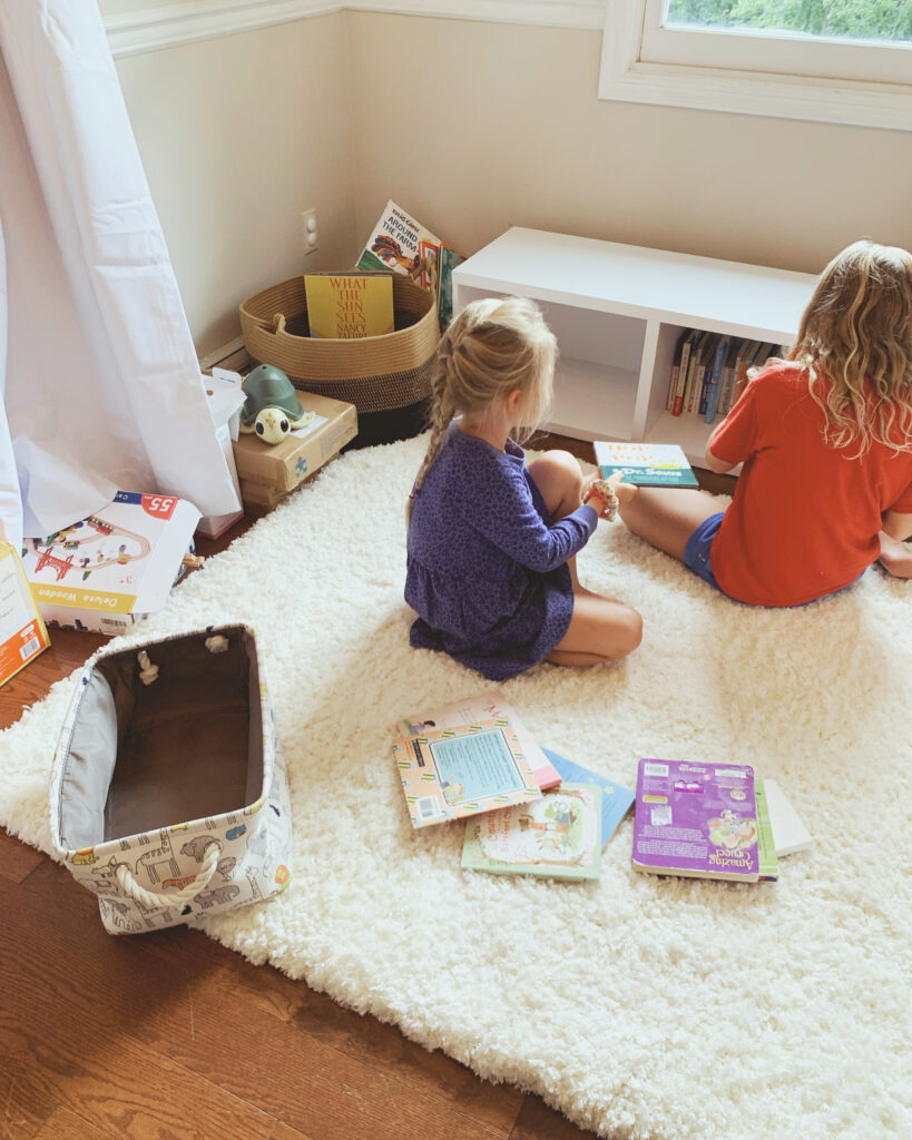 Girls putting books in bookshelf for baby boy nursery 