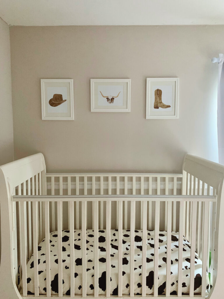 Western baby boy nursery with hanging artwork over crib