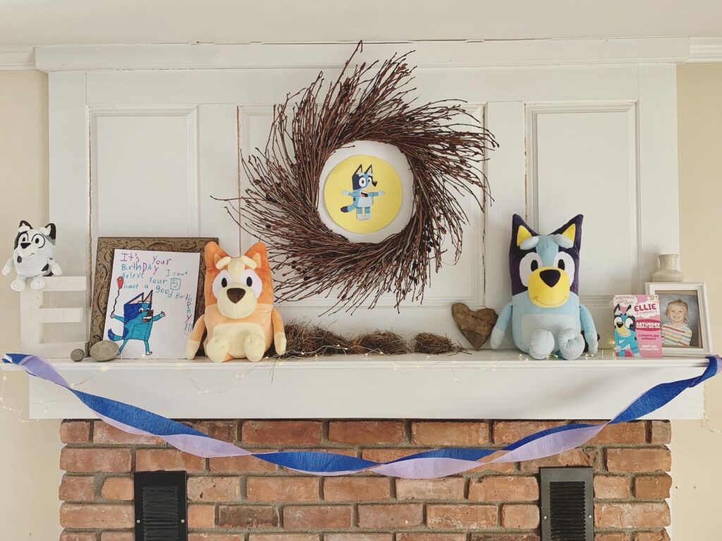 Adorable DIY Bluey Party mantle with plush stuffed animals, streamers and party decor