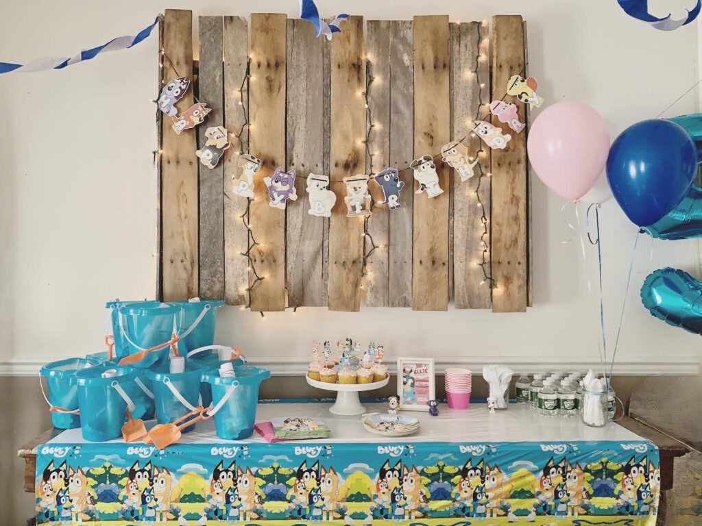 bluey party decor with birthday banner, cupcakes, dessert table, party favors and balloons