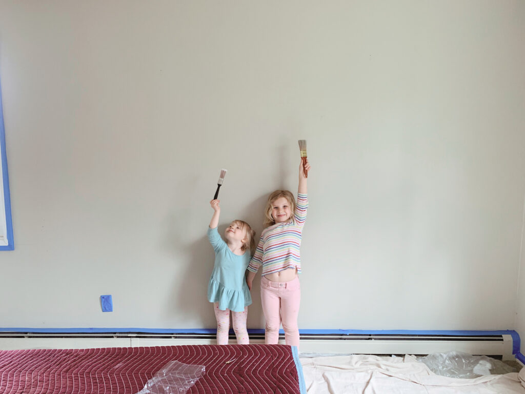 Little girls painting holding up paintbrushes