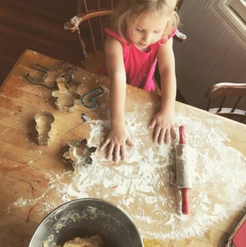 little girl rolling out cookies