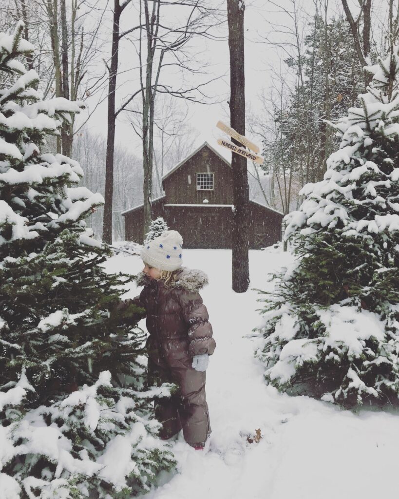 girl in snow in front of snowy barn scene