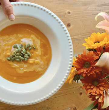 bowl of butternut soup with flowers on table