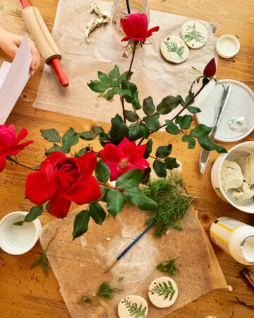 DIY clay ornaments with pine needles and roses on a table