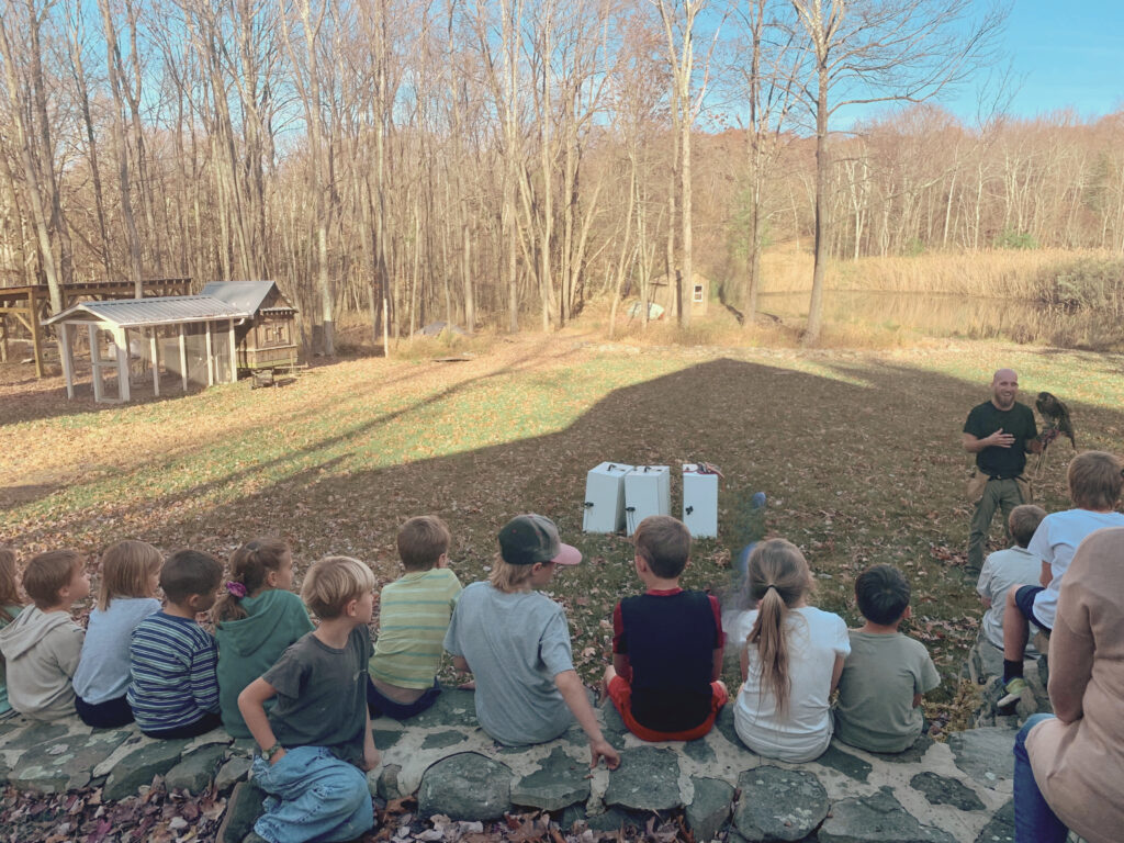 Falconer doing demonstration in front of pond for kids at My Side of the Mountain Book club