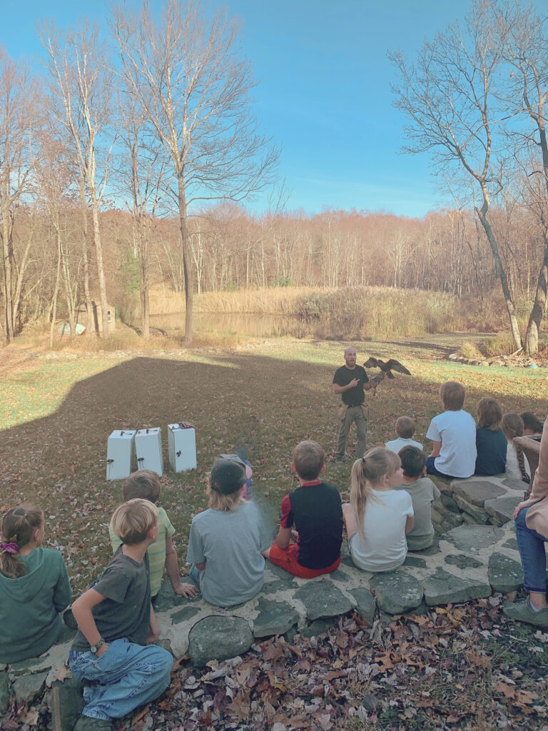 Falconer speaking to kids in front of pond scene