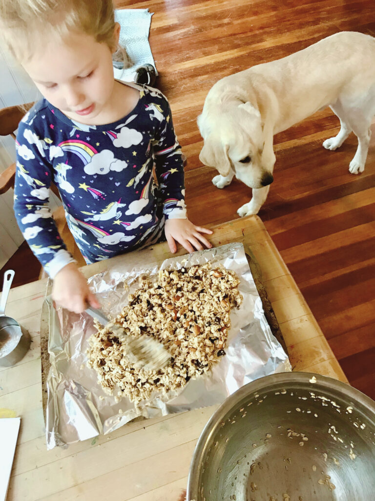 little girl making granola spreading onto pan