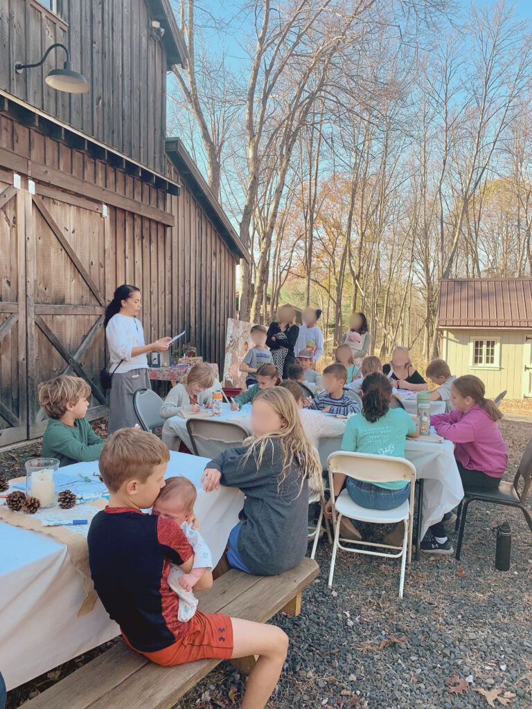 Woman leading book discussion for kids behind post and beam barn