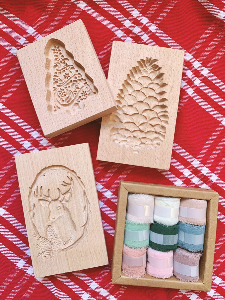 wooden cookie cutters and ribbon on red festive Christmas tablecloth